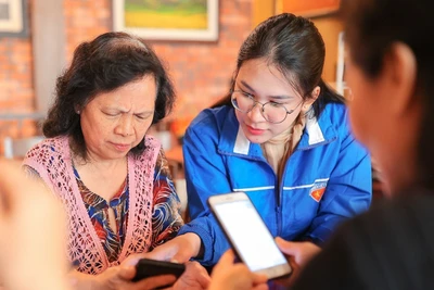 Đoàn viên, thanh niên phường Hoàn Kiếm (Hà Nội) hỗ trợ người dân thực hiện thủ tục hành chính công trên thiết bị điện thoại thông minh. Ảnh: PHẠM HẬU (TTXVN)