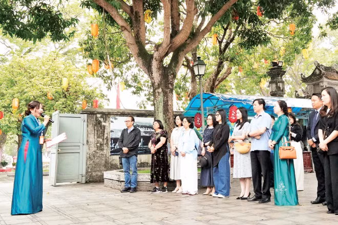 Du khách nghe hướng dẫn viên giới thiệu về Đền Đô (tỉnh Bắc Ninh). (Ảnh: ĐỒNG THÚY)