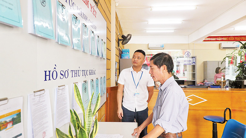 Cán bộ tại Bộ phận "một cửa" UBND xã Ninh Hiệp, huyện Gia Lâm hướng dẫn người dân thực hiện thủ tục hành chính. (Ảnh TUỆ NGHI)