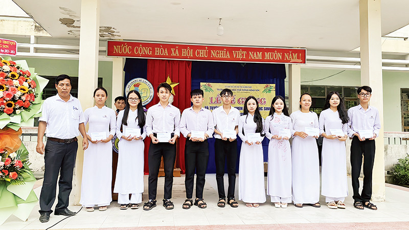 Thầy Trịnh Thanh Thu (bìa trái) trao hỗ trợ cho học sinh. (Ảnh Trường THPT Nông Sơn)
