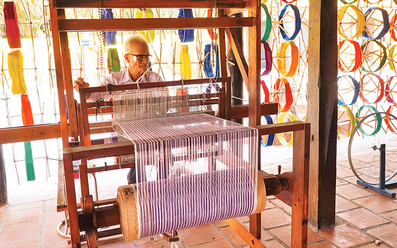 Ông Bảy Nghề trình diễn dệt khăn choàng bằng tay tại Long Khương Miếu, di tích lịch sử cấp tỉnh ở Đồng Tháp.