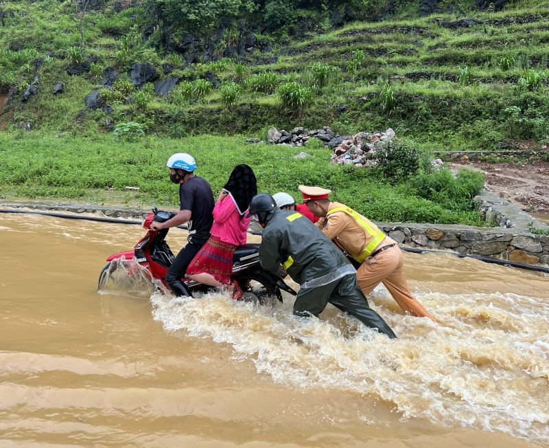 Cảnh sát giao thông Hà Giang lội nước đẩy xe máy, đưa người dân qua điểm ngập an toàn.
