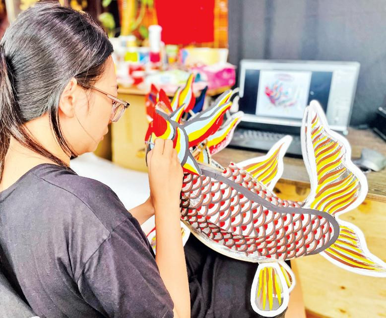 Chị Nguyễn Thị Kim Thủy đang tỉ mỉ từng đường cọ trang trí cho chiếc lồng đèn giấy kiếng "Cá chép hóa rồng".