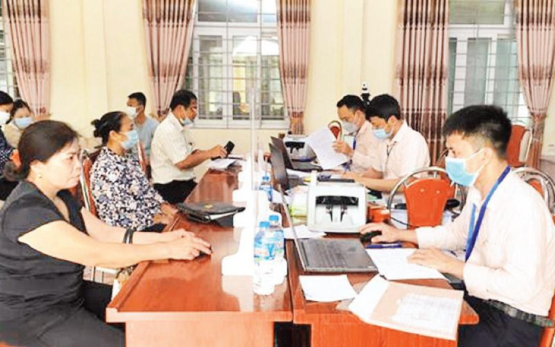 Cán bộ Phòng giao dịch Ngân hàng Chính sách xã hội huyện Phú Xuyên giải ngân nguồn vốn vay ưu đãi giải quyết việc làm cho người dân. (Ảnh HOÀNG HƯƠNG) 