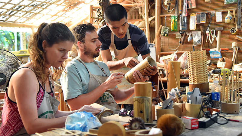 Nhân viên xưởng Taboo Bamboo hướng dẫn du khách hoàn thiện sản phẩm bằng tre. (Ảnh THỦY NGUYÊN)
