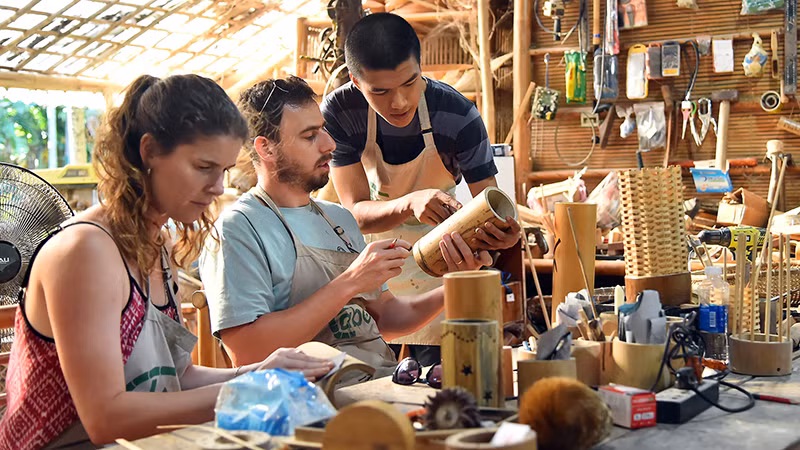 Nhân viên xưởng Taboo Bamboo hướng dẫn du khách hoàn thiện sản phẩm bằng tre. (Ảnh THỦY NGUYÊN)