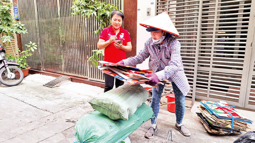 Bà Nguyễn Thị Thanh (áo đỏ), Chi hội trưởng Chi hội phụ nữ Khu phố 3, Phường 6, Quận 10 ghi chép tiền bán ve chai.