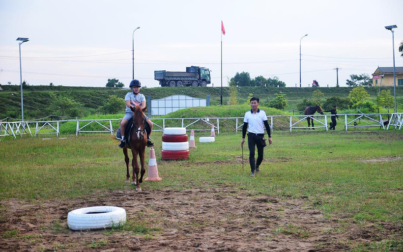 Ðoàn Văn Hưởng hướng dẫn một bé trai cưỡi ngựa.