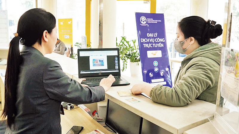 Người dân được nhân viên hướng dẫn làm thủ tục hành chính tại các đại lý dịch vụ công trực tuyến của thành phố Hà Nội.