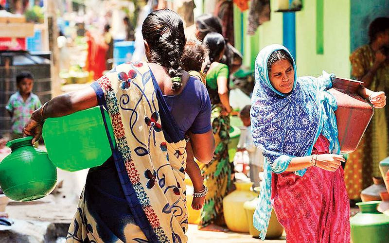 Những phụ nữ mang nước sạch từ vòi công cộng về nhà ở Bengaluru. Ảnh | Manjunath Kiran/ AFP