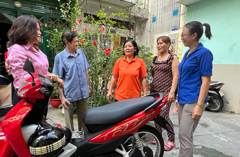 Bà Nguyễn Thị Lý (đứng giữa) và đại diện Mặt trận Tổ quốc Phường 11 (quận Phú Nhuận) bên chiếc xe máy được trao tặng làm phương tiện mưu sinh.