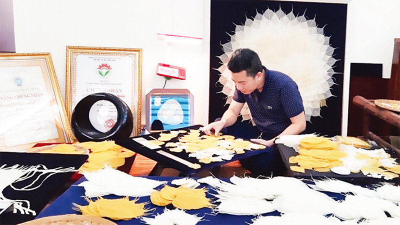 Kiểm tra lá bồ đề nguyên liệu trước khi làm tranh. (Ảnh Hoàng Thanh Phương)