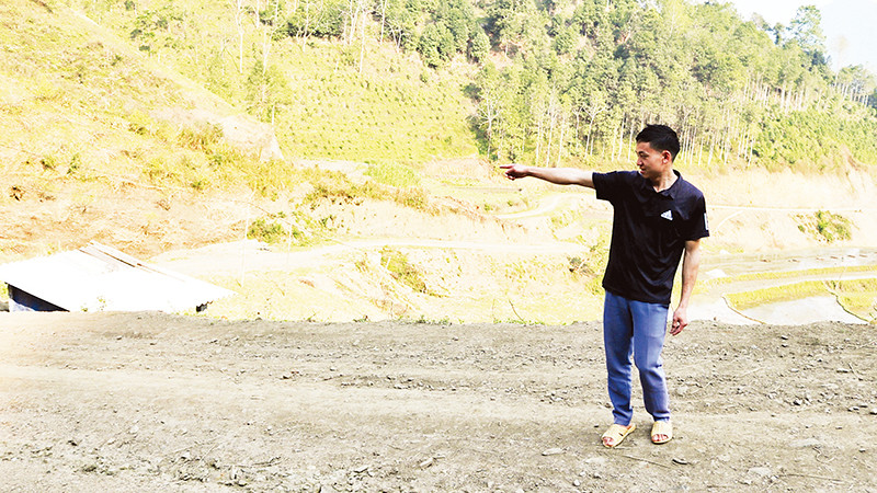 Triệu Tòn Lai chỉ về phía diện tích đất gia đình anh hiến để thực hiện chương trình xây dựng nông thôn mới. (Ảnh NGUYỄN NGHĨA)