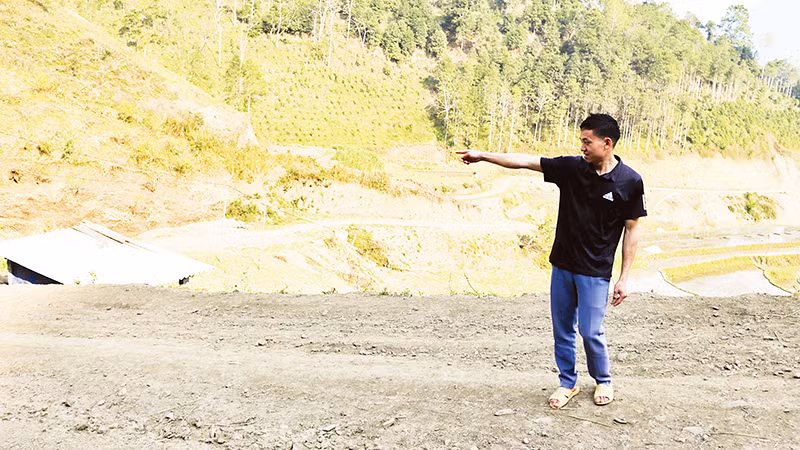 Triệu Tòn Lai chỉ về phía diện tích đất gia đình anh hiến để thực hiện chương trình xây dựng nông thôn mới. (Ảnh NGUYỄN NGHĨA)