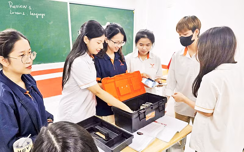 Học sinh lớp 12D1 Trường THPT Lê Hồng Phong cất điện thoại vào hộp đựng đồ trước tiết học đầu tiên. (Ảnh TRẦN SƠN)