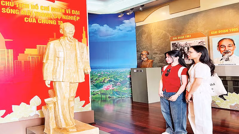 Bạn trẻ thưởng lãm tác phẩm “Bác Hồ về thăm quê hương Nghệ An lần thứ hai” của tác giả Nguyễn Xuân Tiên. (Ảnh MẠNH HẢO).