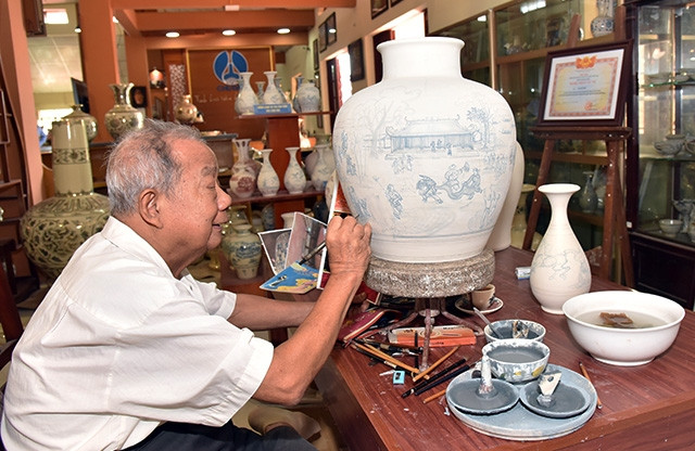 Nghệ nhân Hạ Bá Định vẽ trên bình gốm Chu Đậu. Ảnh: ĐĂNG ANH