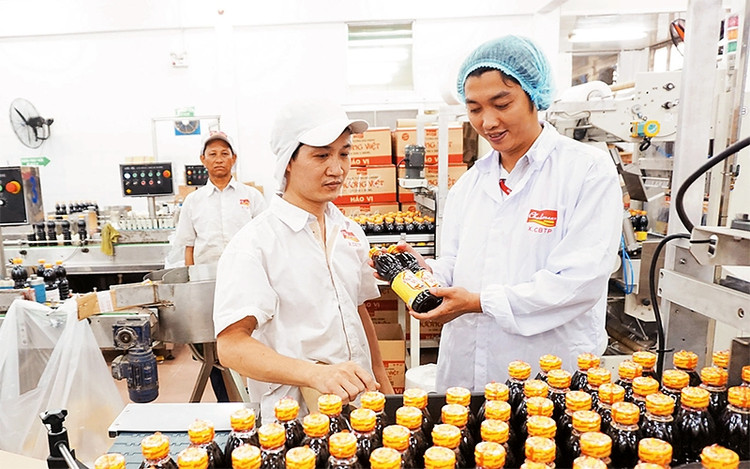 Kỹ sư Lê Ðức Anh (ngoài cùng, bên phải) kiểm tra thành phẩm tại dây chuyền đóng nước tương của Công ty cổ phần Thực phẩm Cholimex.