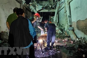 Lực lượng chức năng huy động chó nghiệp vụ tham gia tìm kiếm tung tích những người mắc kẹt trong vụ cháy nhà. (Ảnh: Nguyễn Thành/TTXVN)