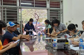 Những người dân chịu ảnh hưởng bởi vụ cháy nhận tiền hỗ trợ. (Ảnh: Việt Tuấn)