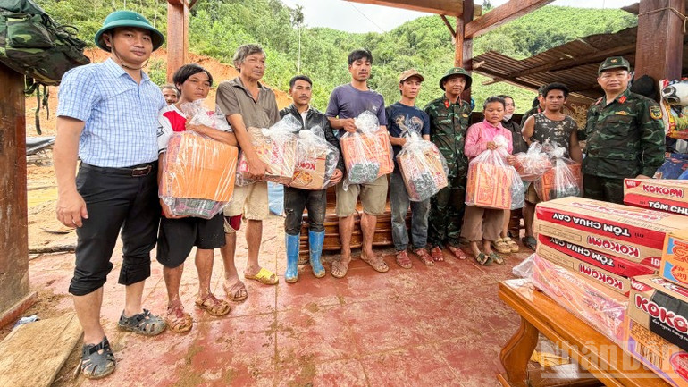 Bí thư Đảng ủy xã Trà Tân Nguyễn Hồng Lai (đứng ngoài cùng đội mũ cối) trao quà cho các hộ dân bị bị cô lập do sạt lở núi. ndo_br_6-6974.jpg