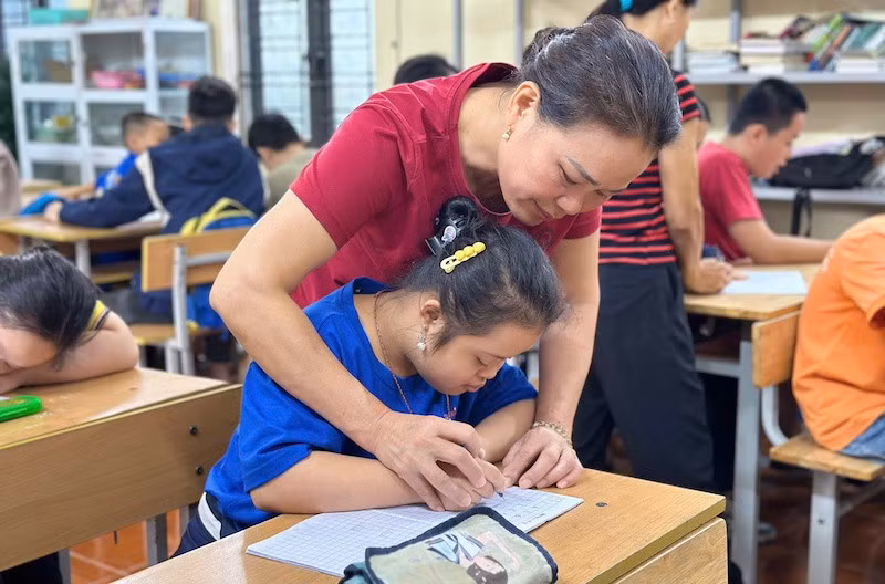 Cô Lê Thị Hòa đang hướng dẫn học sinh viết chữ.