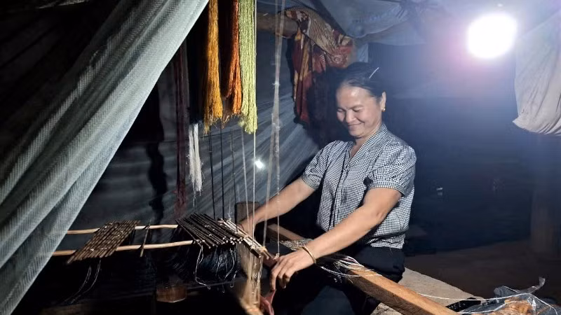 Người dân bản biên giới Cha Nga, xã Mỹ Lý tranh thủ dệt thổ cẩm khi có ánh sáng điện ổn định.