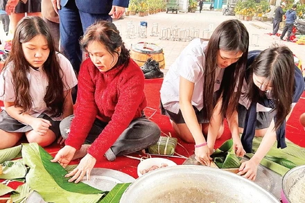Các em học sinh trải nghiệm gói bánh chưng cùng hội viên Câu lạc bộ Liên thế hệ tự giúp nhau phường Khương Đình (thành phố Hà Nội).