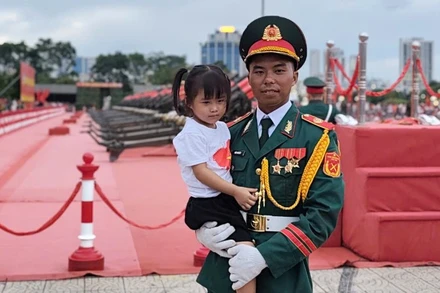 Hình ảnh chiến sĩ pháo binh Đỗ Kim Vũ bế cháu gái đến cổ vũ trong chương trình Tổng hợp luyện diễu binh, diễu hành lần 2. (Ảnh: VĂN THỊNH)