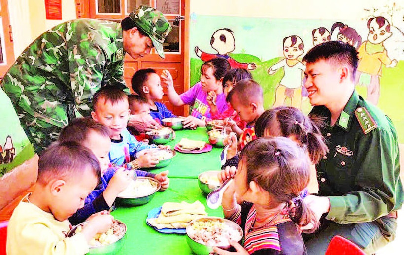 Thiếu tá Cầm Bá Thành (bên phải ảnh) cùng với đồng đội thực hiện “Bữa sáng cho em” tại điểm Trường mầm non Buốc Pát.