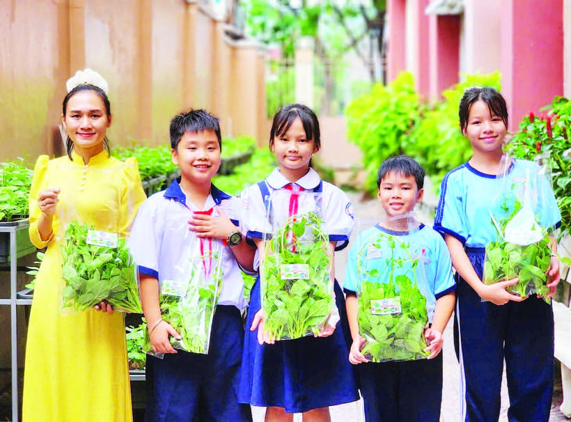 Cô trò Trường tiểu học Đặng Trần Côn (phường Vĩnh Hội) thu hoạch rau tại vườn.
