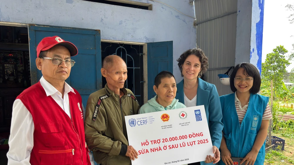 Đại diện Chương trình Phát triển Liên hợp quốc (UNDP) trao tiền hỗ trợ cho gia đình bị ảnh hưởng bởi bão lũ.