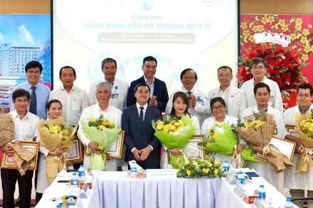 Thứ trưởng Y tế Trần Văn Thuấn tặng hoa và bằng khen cho ekip thực hiện ca can thiệp bào thai cho sản phụ người Singapore. (Ảnh: HOÀNG HÙNG)