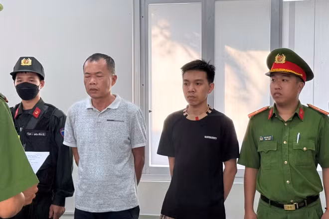 Đặng Trần Quốc Vũ (áo trắng) và Đào Năng Nghĩa (áo đen) nghe đọc lệnh tạm giữ hình sự.