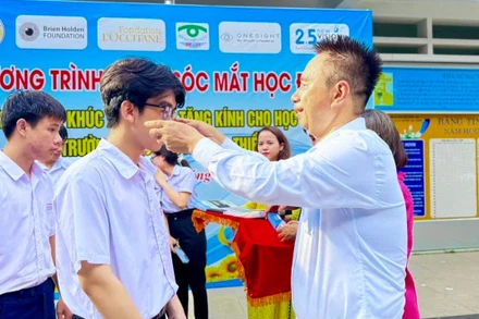 Bác sĩ Nguyễn Viết Giáp mang kính cho học sinh bị tật khúc xạ.