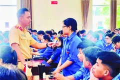Lực lượng cảnh sát giao thông trao đổi, hướng dẫn các kỹ năng xử lý tình huống giao thông cho sinh viên tình nguyện. (Ảnh BẢO LÂM)