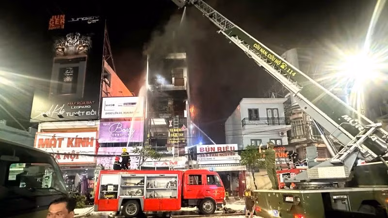 Các chiến sĩ dùng thang xếp leo lên các nhà dân bên cạnh tiếp cận đám cháy.