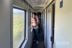 Du khách đứng ngắm cảnh qua khung cửa sổ trên tàu.