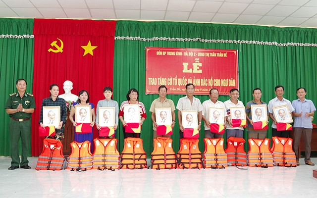 Lãnh đạo địa phương và BĐBP Sóc Trăng trao tặng cờ Tổ quốc, ảnh Bác Hồ và áo phao cho bà con ngư dân.