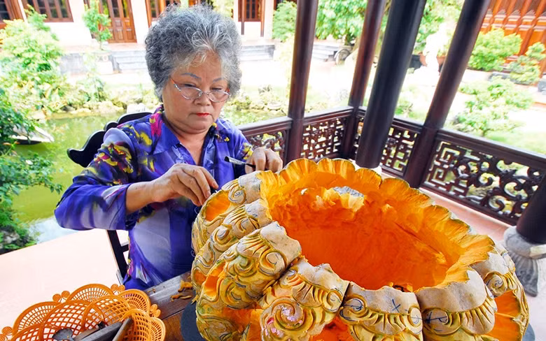 Nghệ nhân Ưu tú Tôn Nữ Thị Hà tỉa chạm quả bí đỏ.