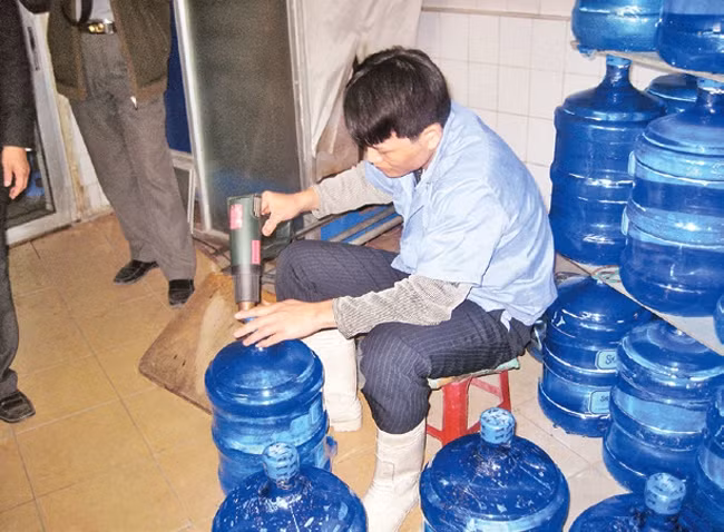 Đóng bình nước một cách thủ công, không tuân thủ quy định vệ sinh tại một cơ sở cung cấp nước "tinh khiết".