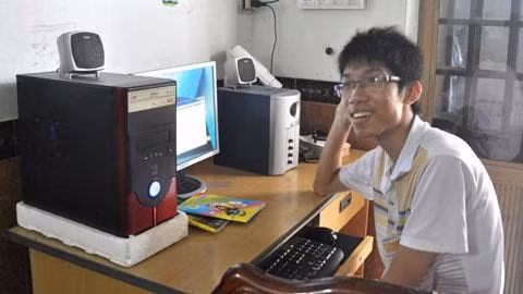 Tân thủ khoa Trần Nhật Hoàng bên bộ vi tính cũ người anh họ vừa tặng.