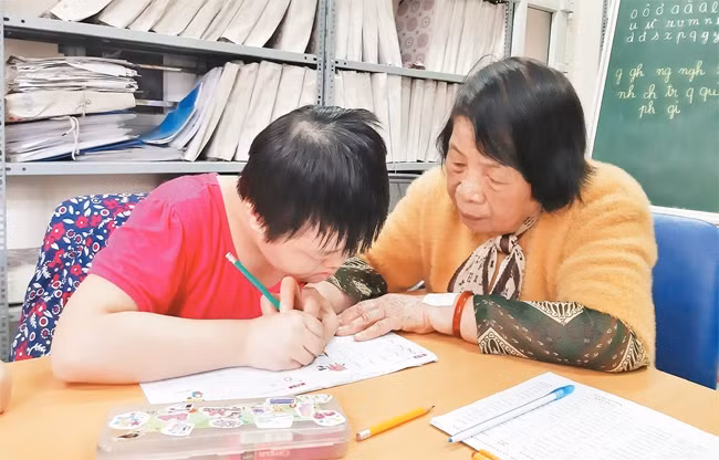 Bà giáo Nguyễn Thị Côi hướng dẫn học sinh lớp học tình thương tập viết. 