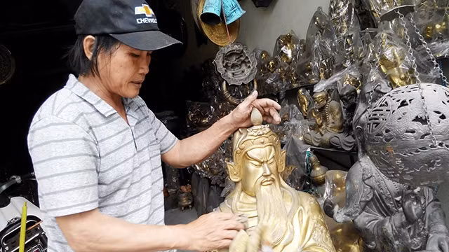 Nghệ nhân Dũng bên tượng đồng.