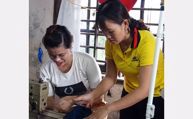 Chị Phạm Thị Luyện hướng dẫn công nhân khuyết tật quy trình may sản phẩm.