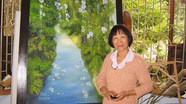 Nhà văn Đoàn Lê bên một bức tranh trong ngôi nhà bên biển.