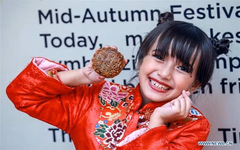 Bé gái chụp ảnh cùng chiếc bánh Trung thu tại trung tâm thương mại ở Manila, Philippines, ngày 11-9. (Ảnh: Tân Hoa xã)
