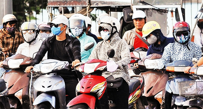 Người dân khi ra đường thường xuyên phải đeo khẩu trang đề phòng khói bụi từ các loại xe sử dụng xăng, dầu. Ảnh: KHÁNH AN