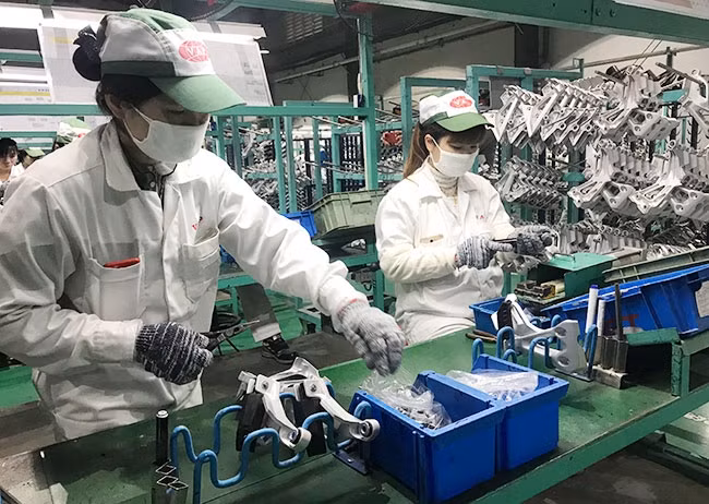 Công nhân Công ty TNHH sản xuất phụ tùng ô-tô và xe máy Việt Nam (Hưng Yên) trong ngày làm việc đầu tiên sau kỳ nghỉ Tết Nguyên đán.