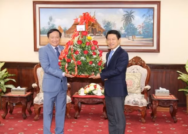 Đại sứ Việt Nam tại Lào Nguyễn Bá Hùng (trái) trao lẵng hoa chúc mừng Bộ trưởng Ngoại giao Lào Saleumxay Kommasith nhân dịp Tết cổ truyền 2019 của Lào